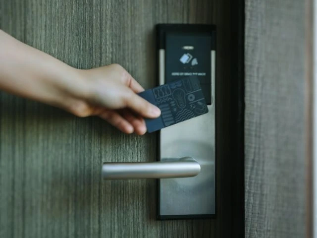 Persona utilizando tarjeta RFID en cerradura inteligente instalada en puerta moderna como parte de los servicios avanzados de cerrajería de Jumaser