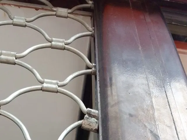 Cierre metálico tipo ballesta parcialmente abierto, utilizado en la protección de comercios y reparado por Jumaser