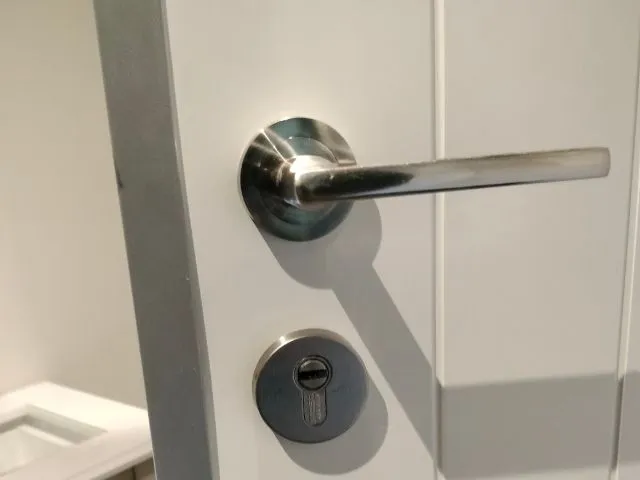 Cerradura moderna con manilla metálica instalada en puerta blanca en servicio de cerrajería en Atocha
