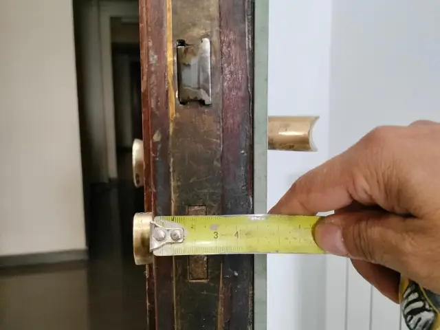 Cerrajero de Jumaser midiendo puerta de madera para instalación de cerradura en Alcalá de Henares